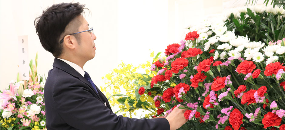 家族葬の長坂式典センター葬儀スタッフが葬式祭壇の生花を整えている様子
